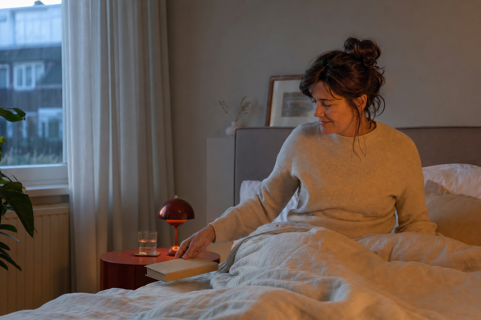 Vrouw legt in de avond een boek naast haar bed